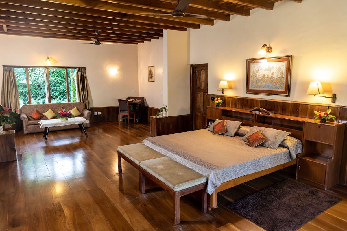 Un dormitorio amplio con una cama grande, muebles de madera, un banco y un escritorio.