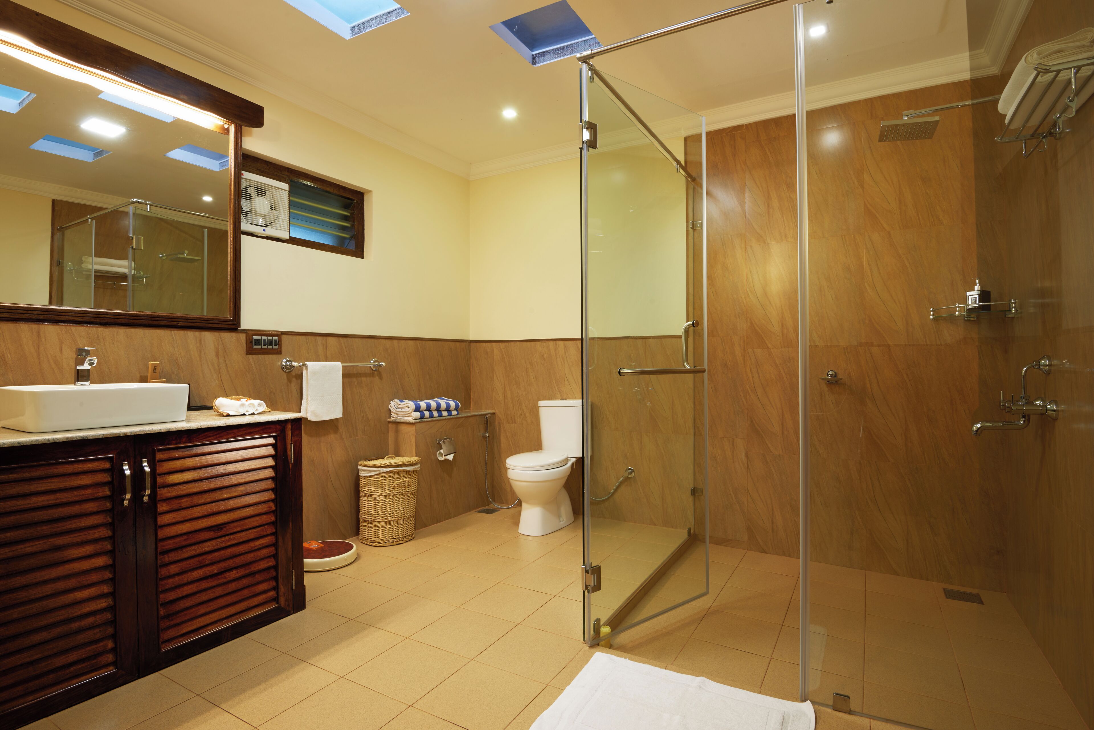 A modern bathroom with a glass shower enclosure, a wooden vanity, and a large mirror.