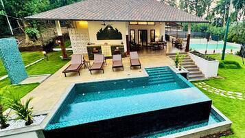 Una casa moderna con piscina, mobiliario exterior y un jardín bien cuidado.