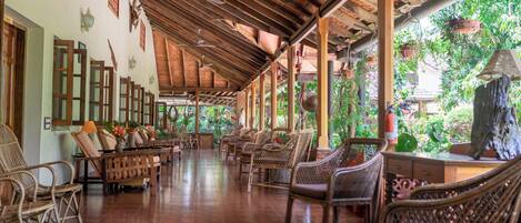 A covered outdoor seating area with wicker furniture and a tiled floor.