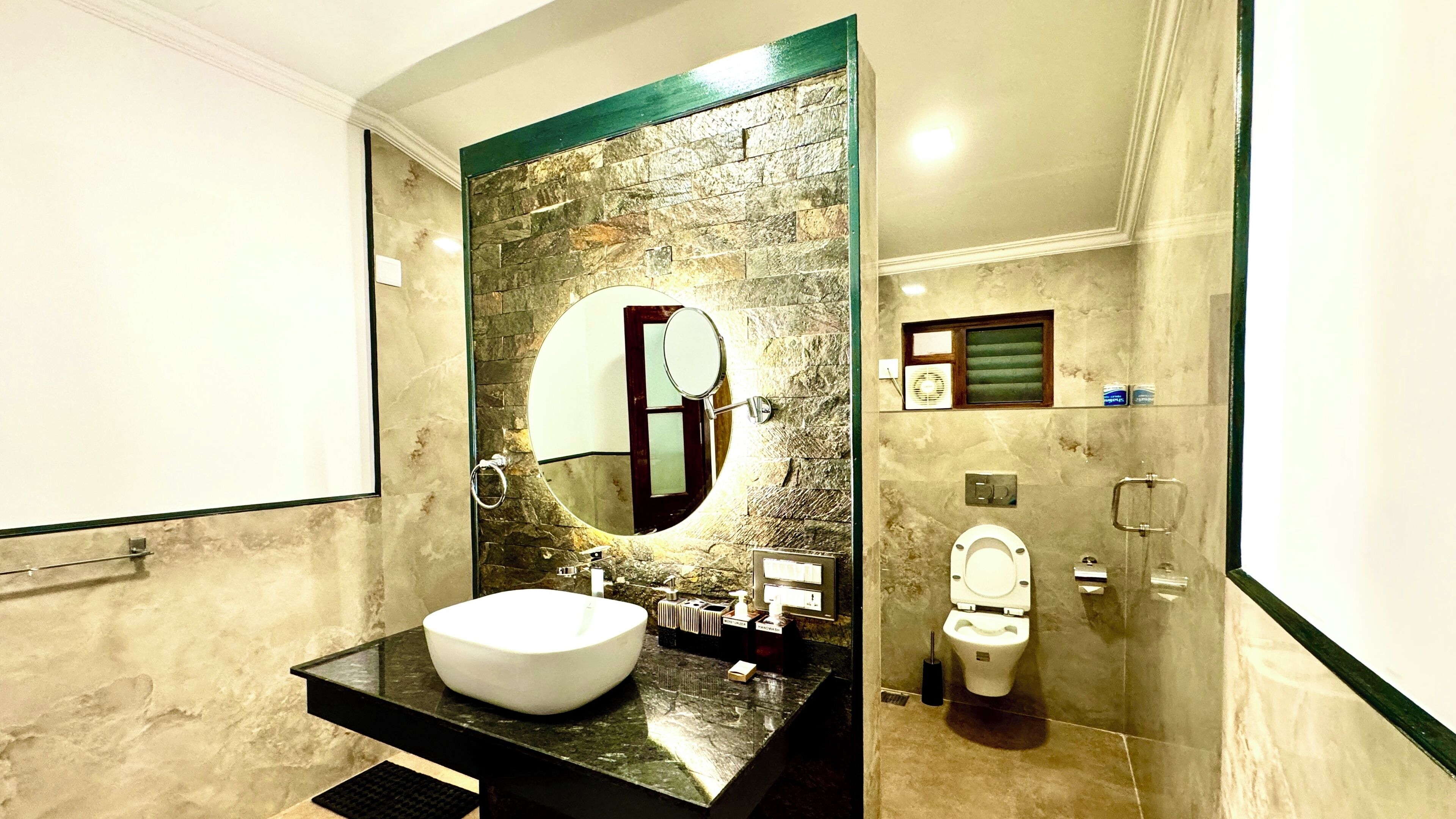 Une salle de bain avec un grand miroir, un lavabo blanc, des toilettes et un espace douche.