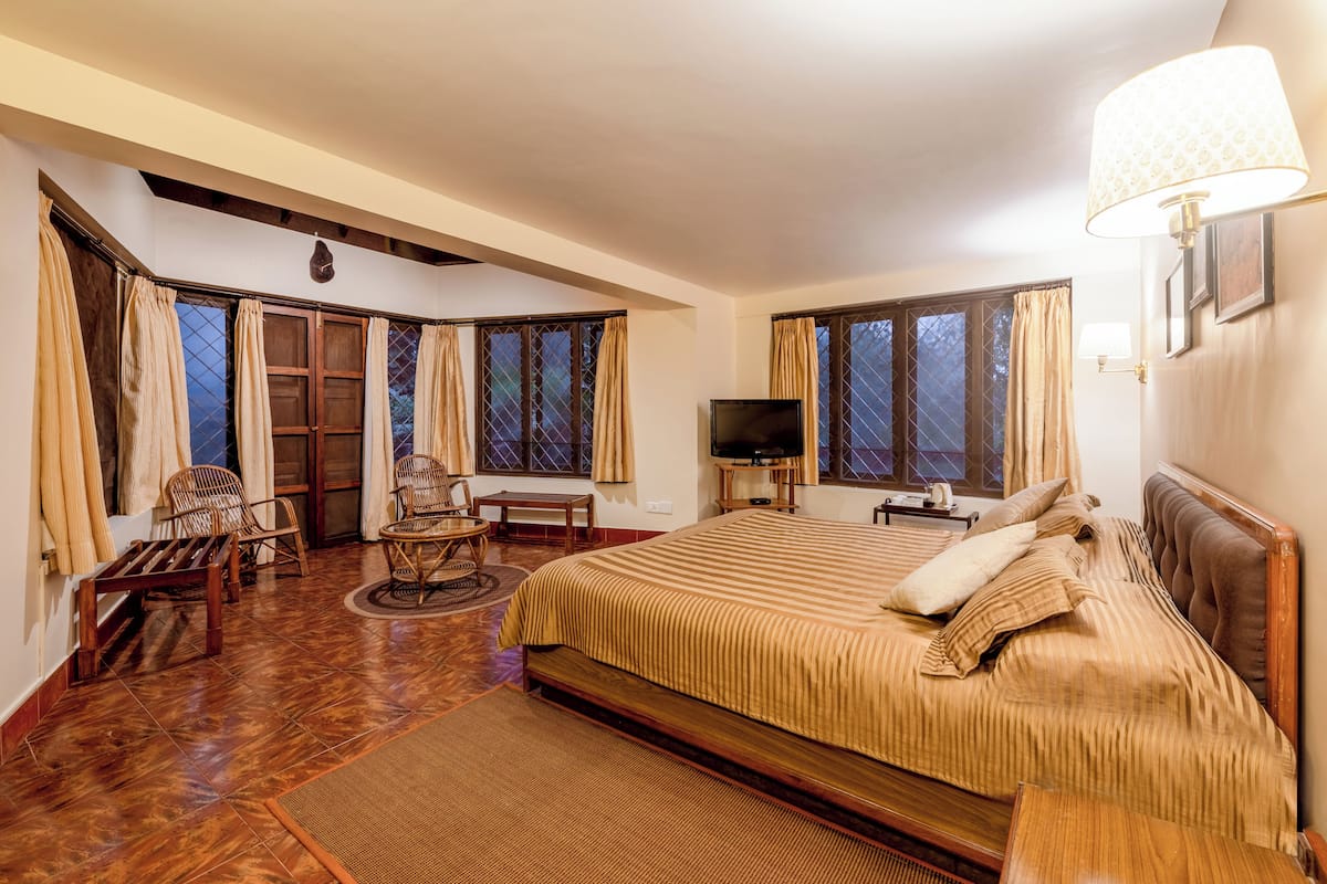 Un dormitorio amplio con una cama grande, televisor y una zona de estar con sillas y una mesa.