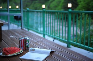 A wooden table with a plate of watermelon slices, two cans of Heineken beer, and an open magazine. - Jirisan Valley Pension (Namwon)