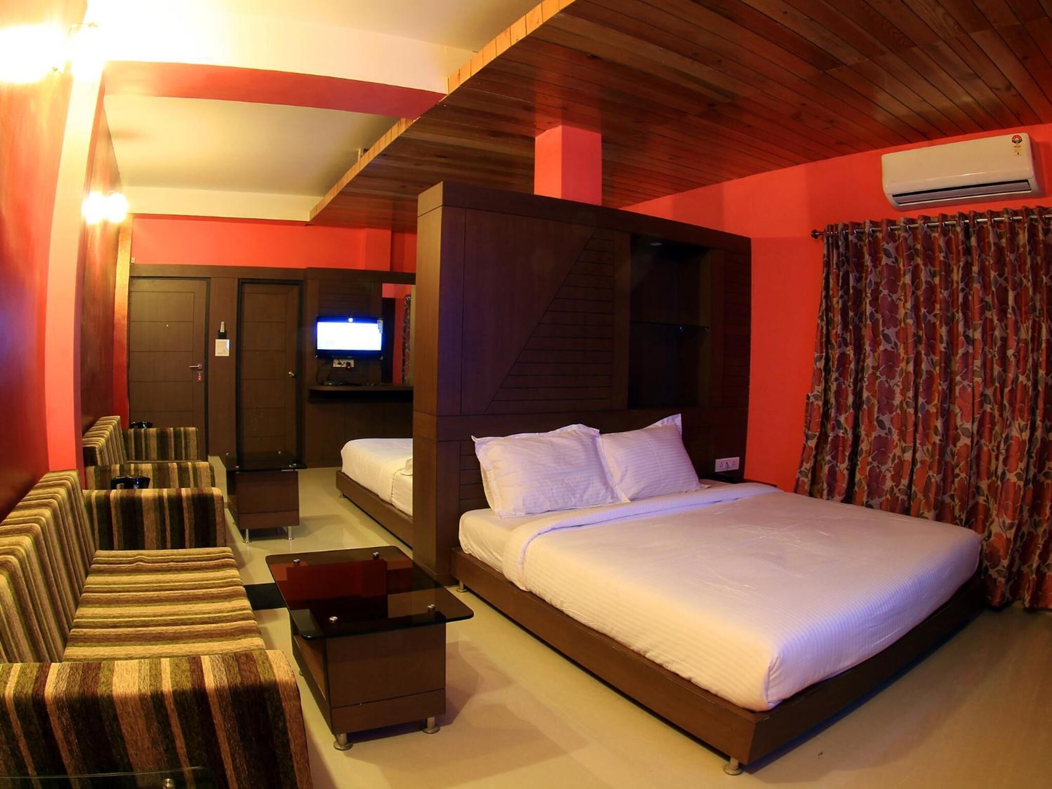 A hotel room with a large bed, a TV, a seating area with chairs, and a small table.