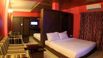 A hotel room with a large bed, a TV, a seating area with chairs, and a small table.
