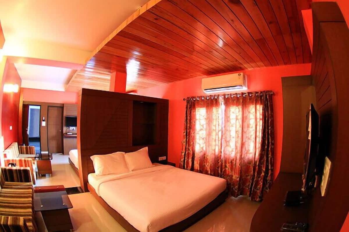 Quarto de hotel com teto de madeira, uma cama, uma TV e uma janela com cortinas.