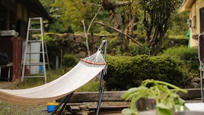 A hammock in a garden with a ladder, wooden bench, and a blue bucket. - Satoyama Guest house COUTURE - Hostel (Ayabe)