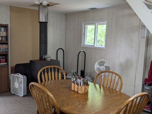 Un comedor con una mesa de madera, cuatro sillas, una lámpara de mesa central y un ventanal con vistas a la vegetación.