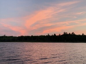Un lago tranquilo al atardecer con una orilla arbolada.