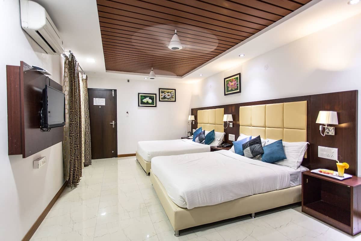 A hotel room with two beds, a TV, a ceiling fan, and a wall-mounted air conditioner.