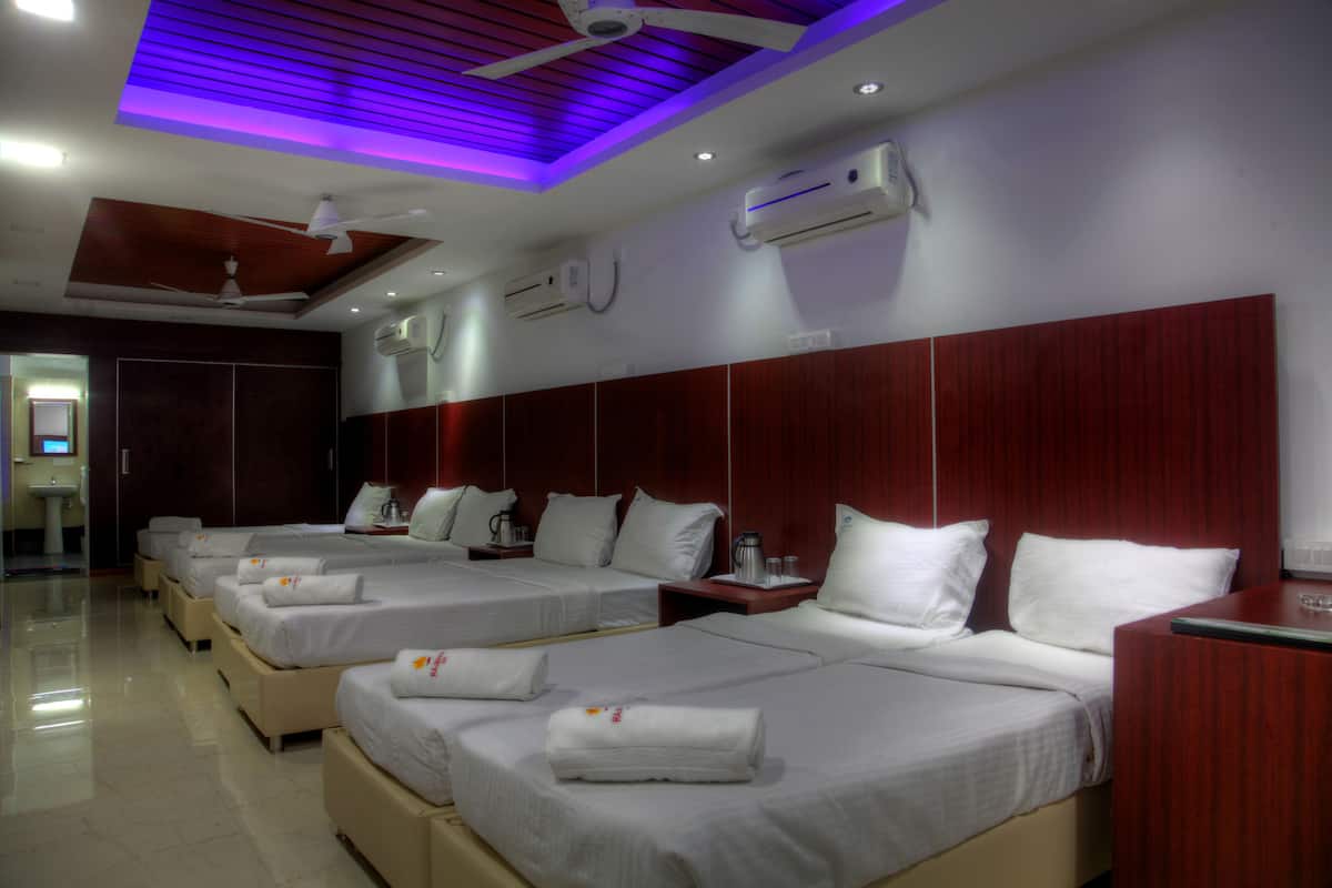 A hotel room with multiple beds, air conditioning units, ceiling fans, and a modern design.