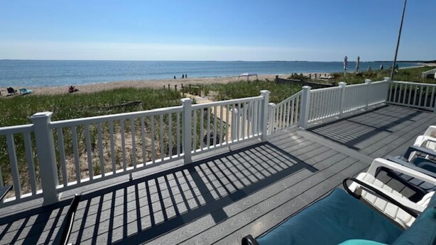 A deck with a view of the beach and ocean.