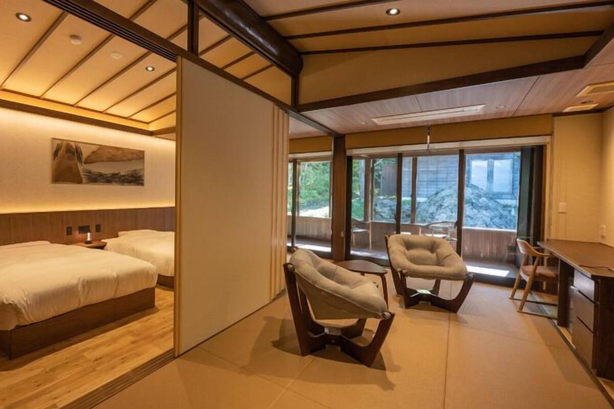 A hotel room with two beds, a desk, and a chair.