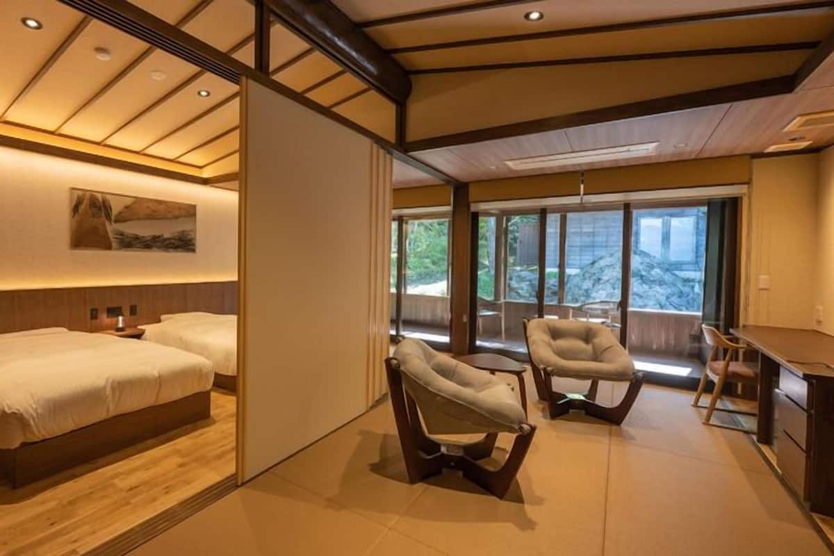 A hotel room with two beds, a desk, and a chair.
