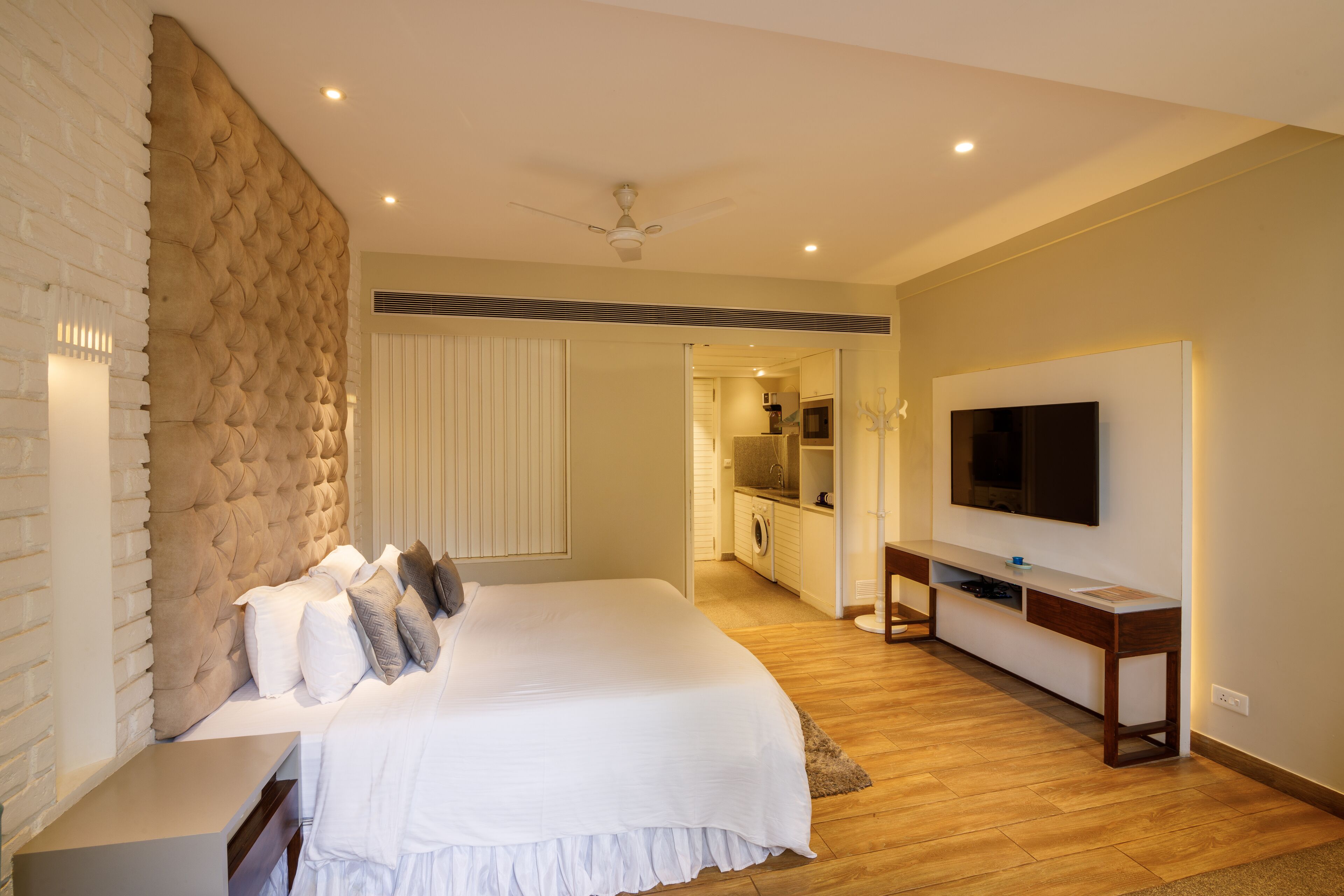 Quarto moderno com uma cama grande, TV na parede e armário embutido.