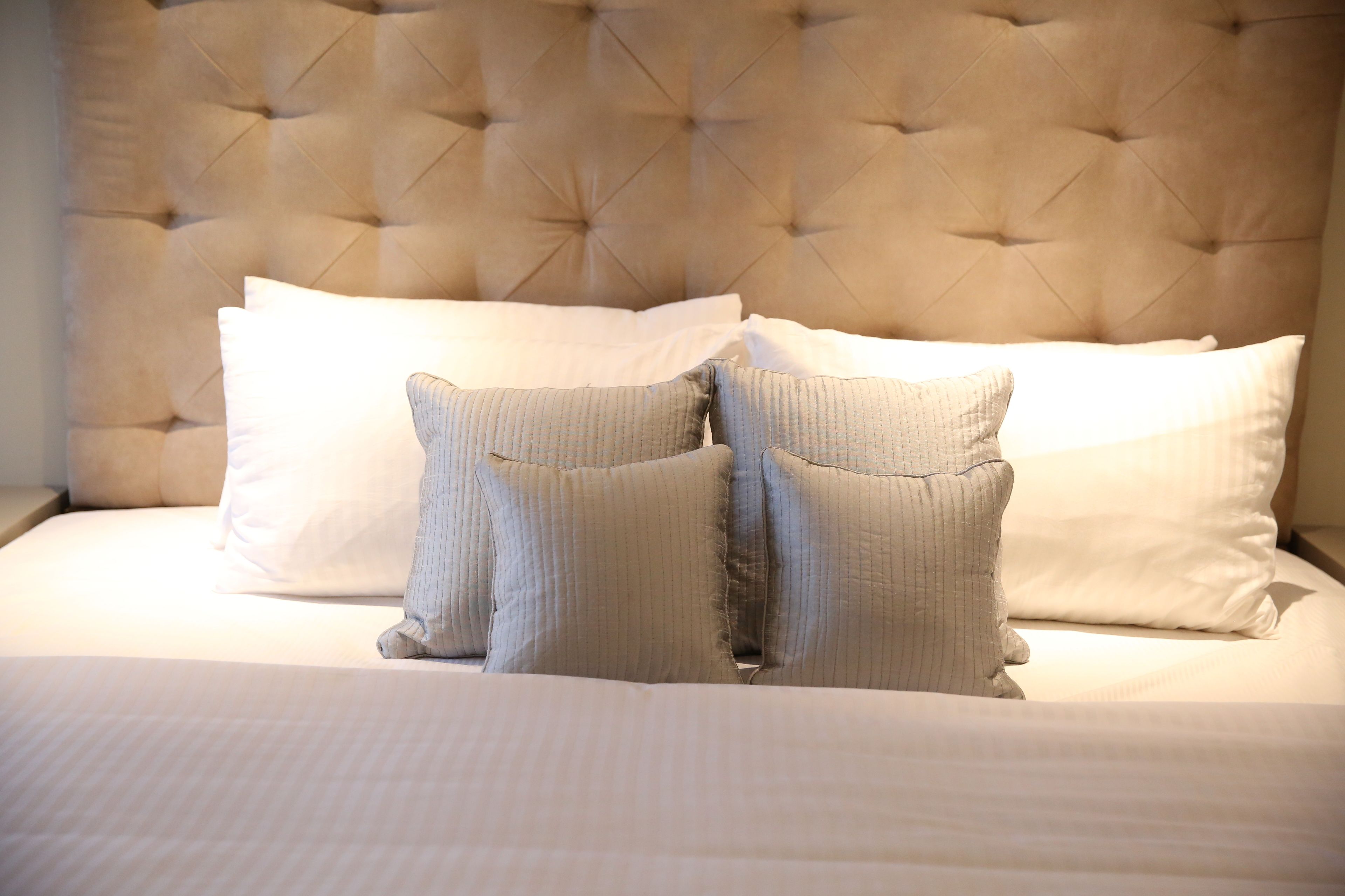 A bed with a tufted headboard, white bedding, and two pillows.