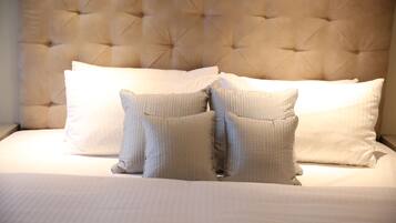 A bed with a tufted headboard, white bedding, and two pillows.