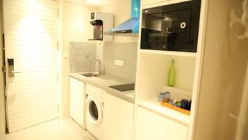 Una cocina funcional equipada con lavadora, cafetera y microondas.