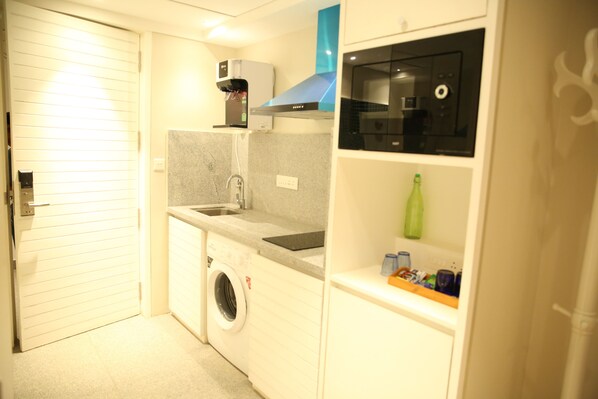A compact kitchen with a washing machine, a coffee machine, and a microwave. - Villa Donna (Panaji)