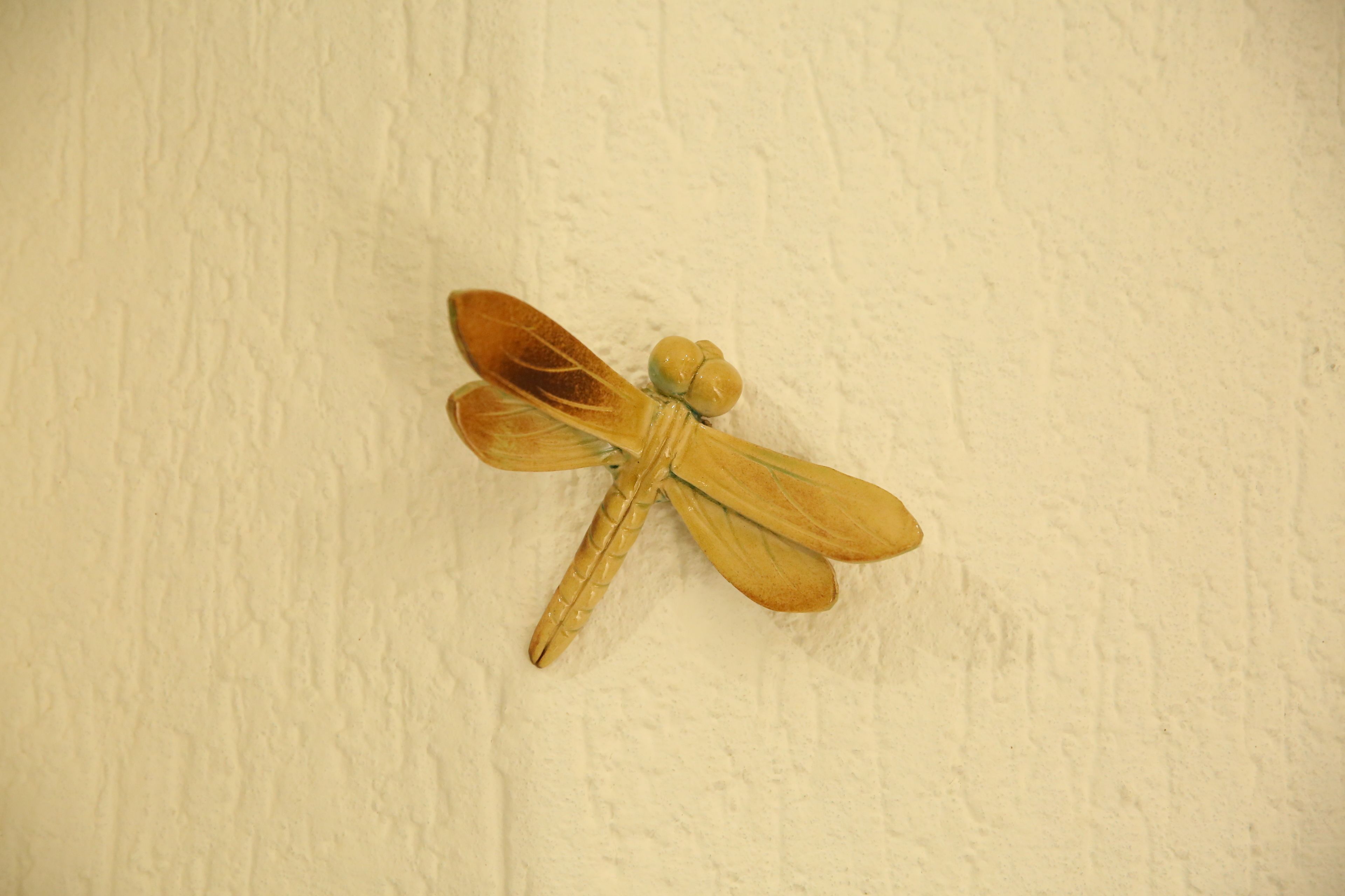 Una decoración de libélula de madera sobre una pared con textura.