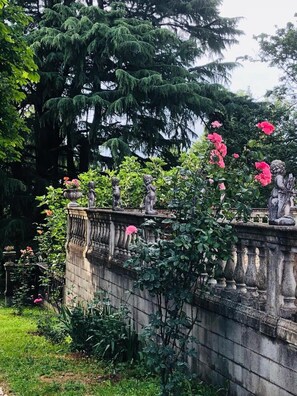 A stone wall with statues and flowering plants. - Charme of Villa Capannina (Novi Ligure)