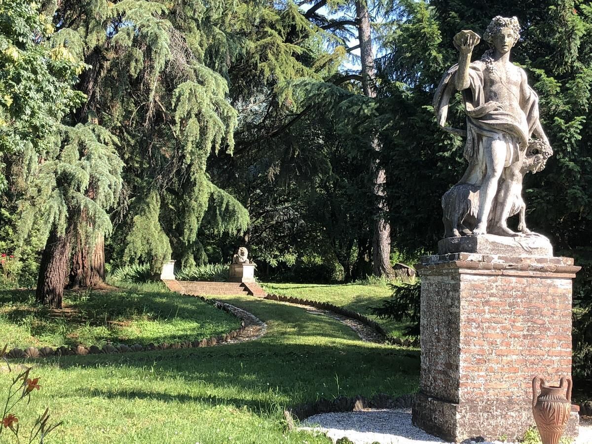 A statue in a park with a pathway and trees.