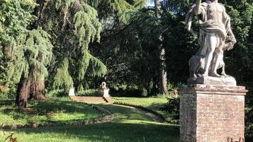 A statue in a park with a pathway and trees.