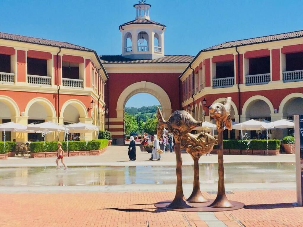 A courtyard with a fountain, red and white buildings, and a bell tower.