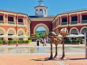 A courtyard with a fountain, red and white buildings, and a bell tower. - Charme of Villa Capannina (Novi Ligure)