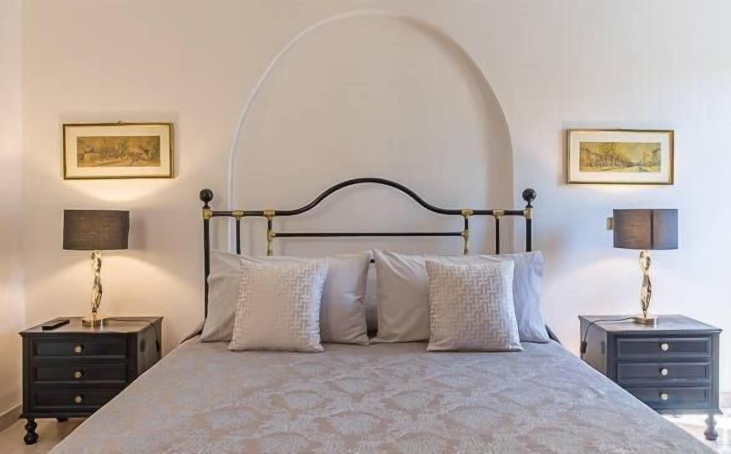 A neatly arranged bedroom with a bed, two bedside tables, and two wall-mounted lamps.