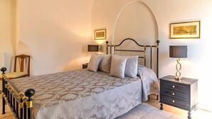 Une chambre à coucher comprenant un lit, des tables de chevet, une commode et une chaise.