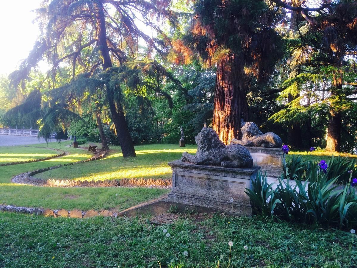 Una fuente de piedra con leones en un parque con árboles y césped.