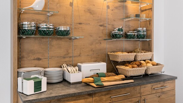 A buffet setup with glass shelves, baskets, and kitchenware. - Hotel Kern (Walddorfhäslach)