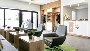 A hotel lobby with seating, a reception desk, and a wardrobe with hanging clothes. - Hotel Kern (Walddorfhäslach)