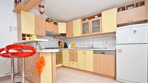 Een keuken met houten kastjes, een witte koelkast en twee rode barkrukken.