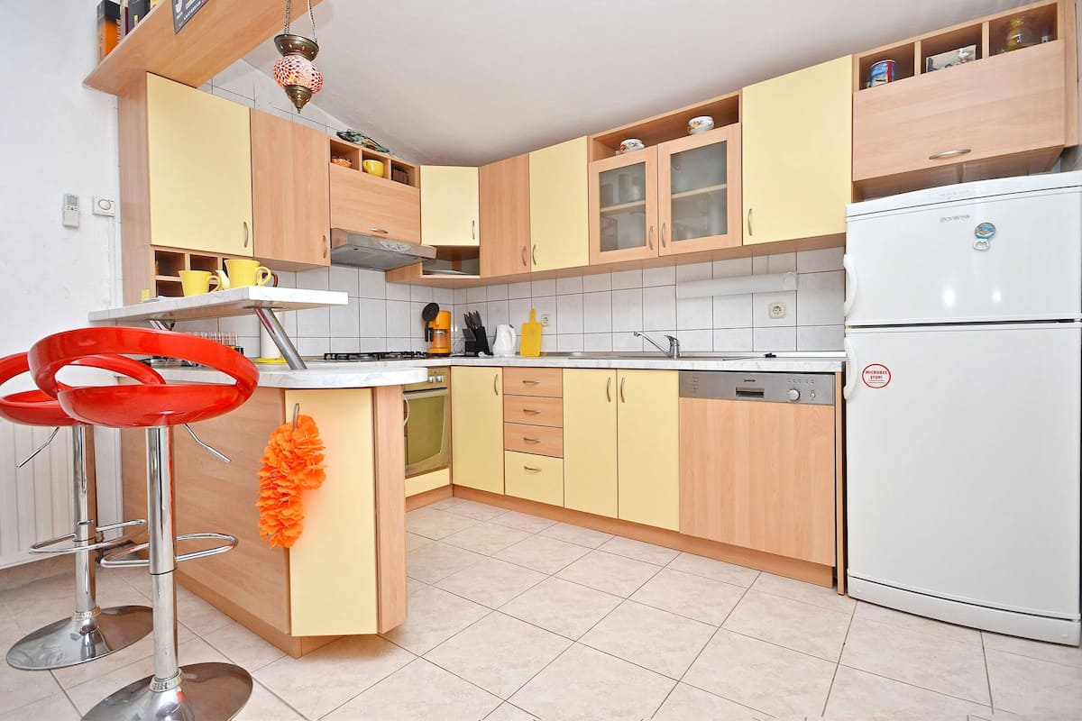 A kitchen with wooden cabinets, a white refrigerator, and two red bar stools.