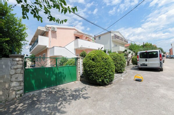 A residential street with houses, a green gate, and a parked van.