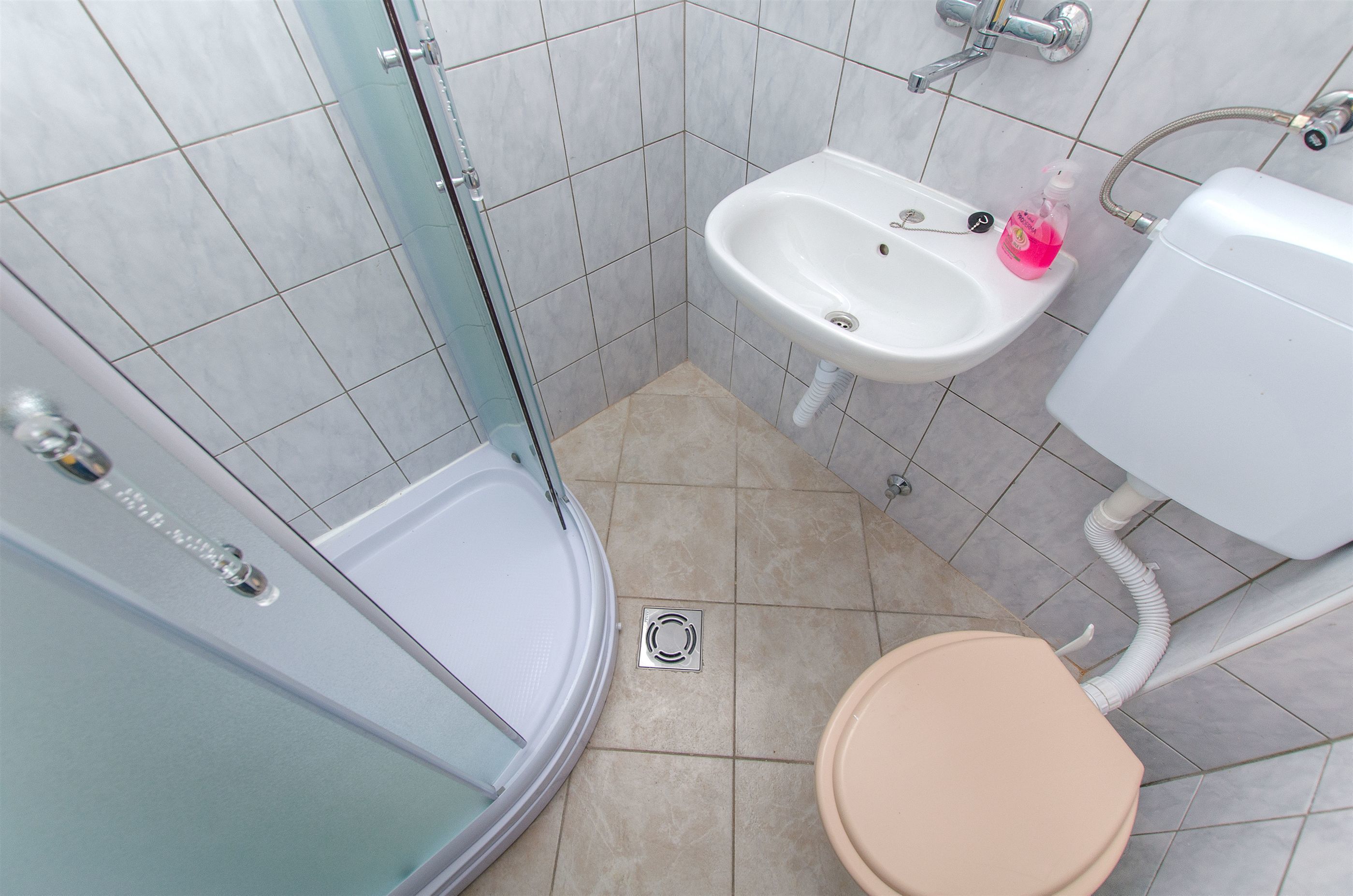 A bathroom with a shower, sink, toilet, and a glass door.