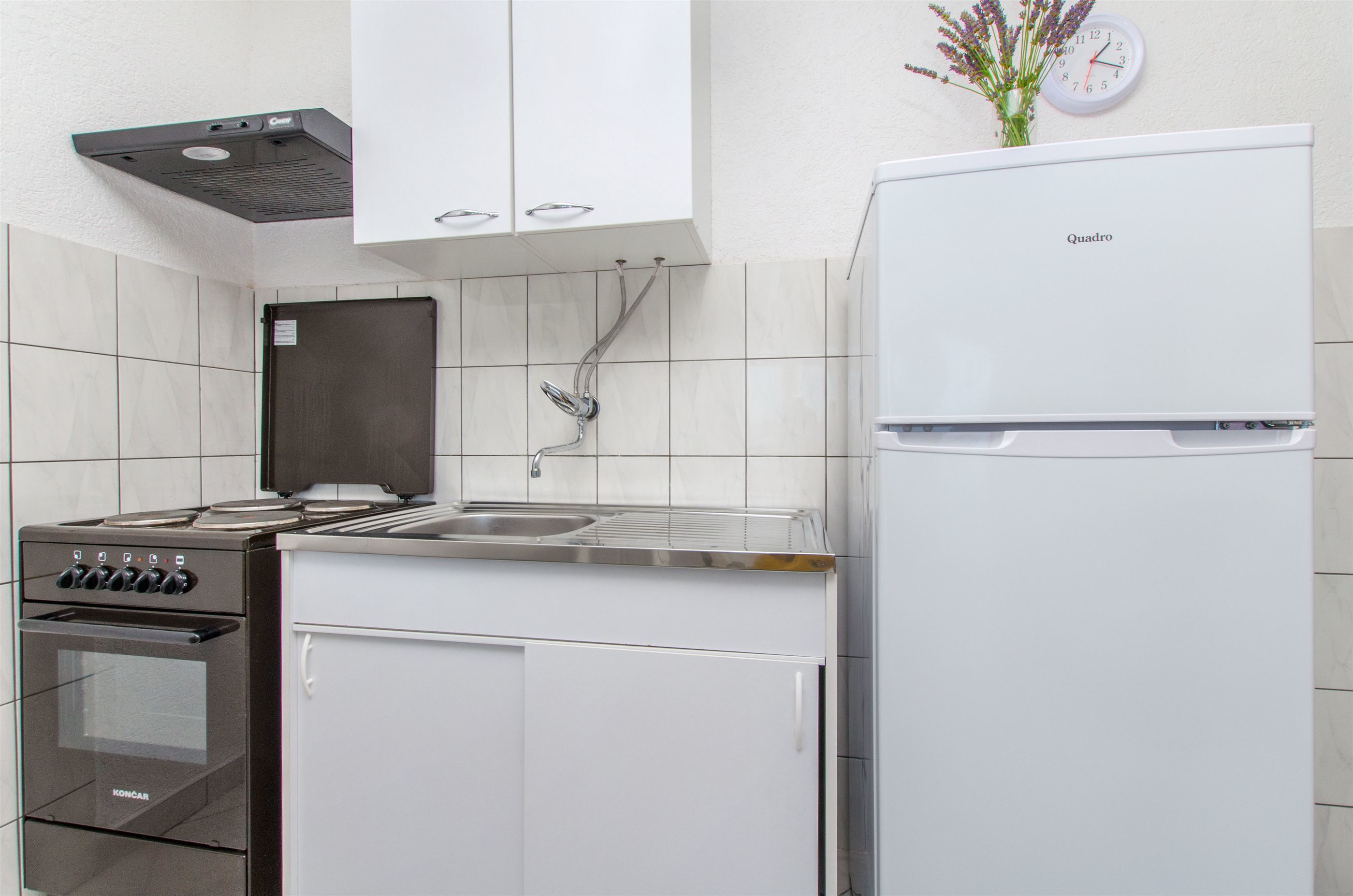 A kitchen with a stove, oven, sink, and a white refrigerator.