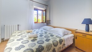 A bedroom with a bed, a window, a radiator, a nightstand, and a lamp. - Apartments Jaksa (Jelsa)