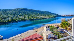 Vista costera con río, playa y colina con vegetación.