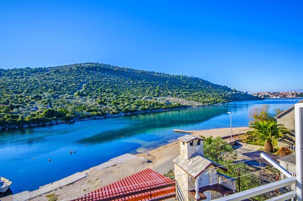 A coastal view with a river, a beach, and a hill with greenery.