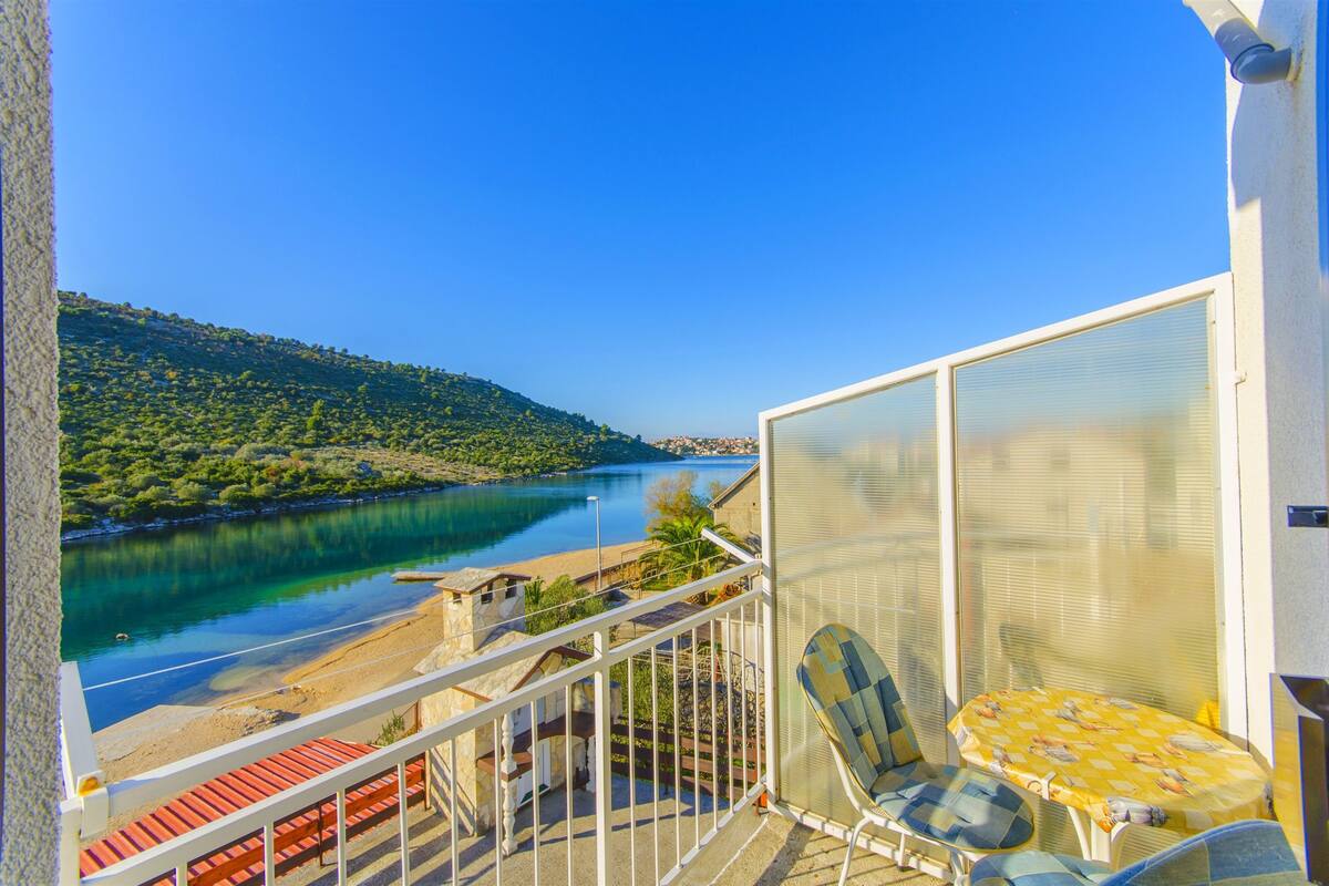 A balcony with a view of a lake and a hilly landscape.