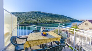 Un balcón con mesa y sillas con vistas a un lago y colinas.