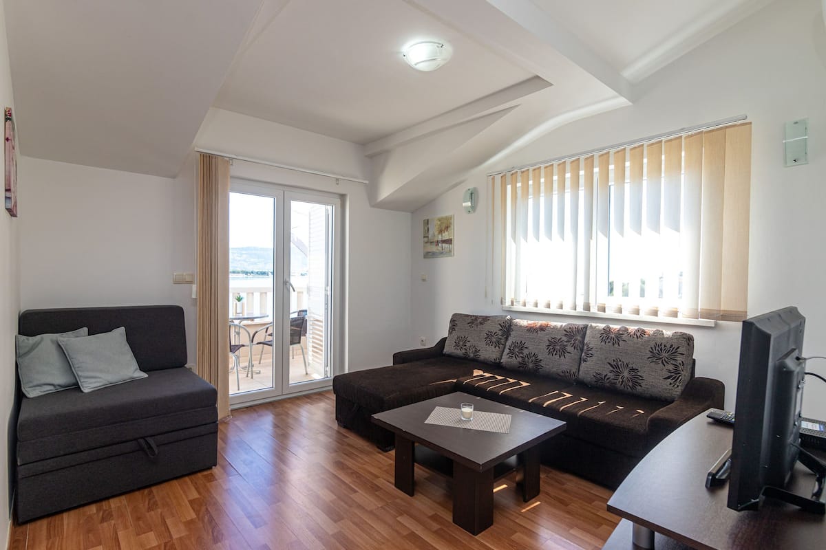 A living room with a sofa, a coffee table, a TV, and a sliding glass door leading to an outdoor area.