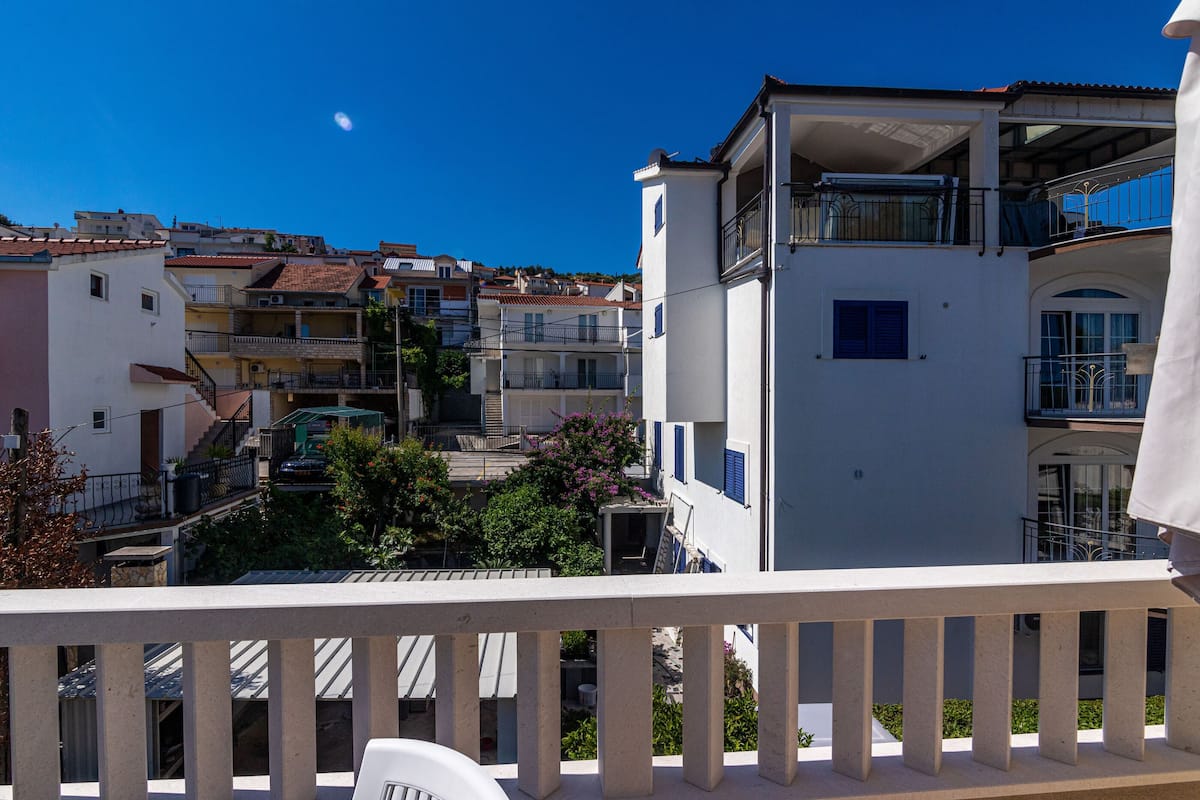 A residential building with multiple balconies, a clear sky, and a visible moon.
