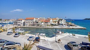 A coastal town with a marina, parked cars, and buildings with red roofs. - Apartments Mira (Tribunj)