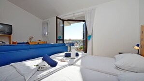 A hotel room with a bed, a TV, a balcony, and a view of the city. - Apartments Mira (Tribunj)