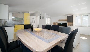Cozy living space with a central dining table and kitchen area featuring a microwave, kettle, and television.