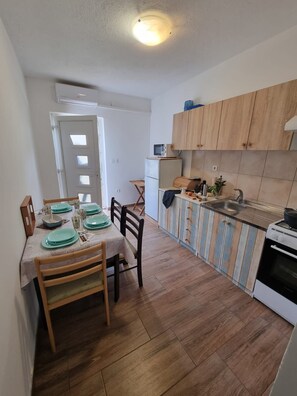 Une cuisine de taille réduite, dotée de meubles en bois, d’un four à micro-ondes et d’un évier.